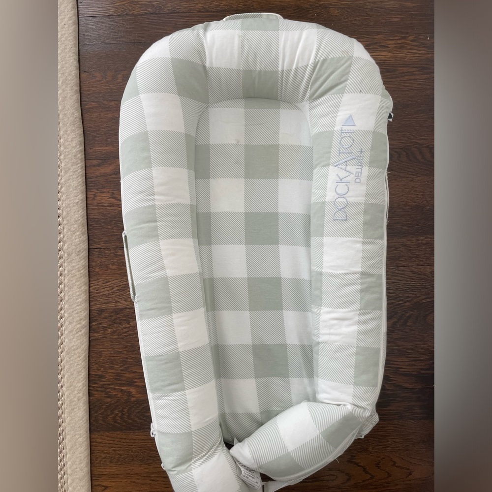 DockATot Deluxe+ with white and plaid covers